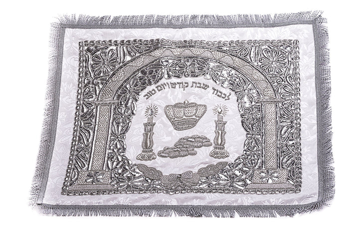 White and silver-tone challah cover with an arch, crown, candlesticks, challah loaves, Hebrew text and fringed edge