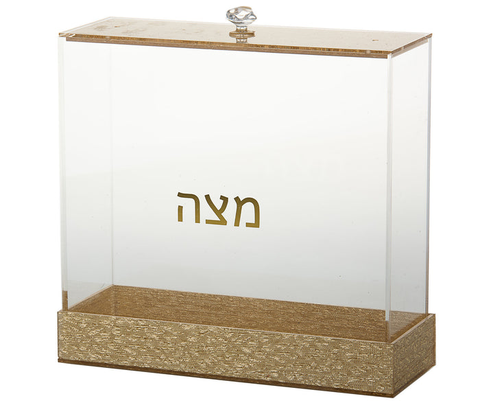 Clear Lucite matzah box on a gold-tone base with gold Hebrew Matzah lettering and knobbed lid