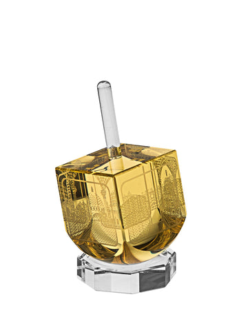 Amber crystal dreidel with gold-tone Jerusalem scene engravings and clear stem on a clear octagonal stand