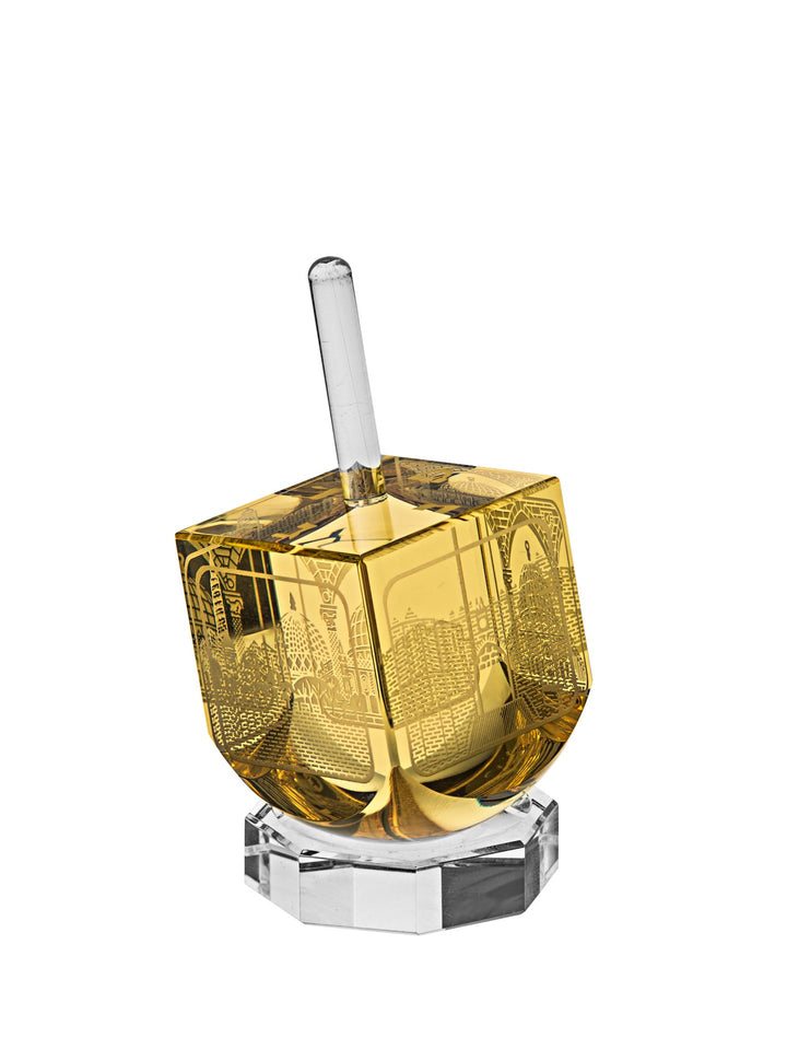 Amber crystal dreidel with gold-tone Jerusalem scene engravings and clear stem on a clear octagonal stand