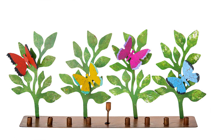 Metal menorah with red, yellow, pink and blue butterflies on green leaf stems above a copper-tone base