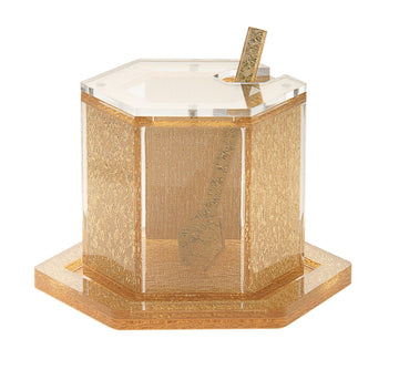 Lucite honey dish and its matching spoon resting on a polished gold tray