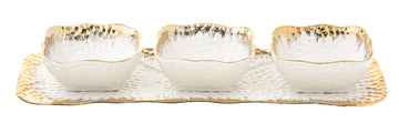 Three small gold rimmed porcelain bowls lined up along a narrow rectangular tray