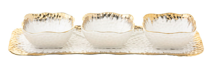 Three small gold rimmed porcelain bowls lined up along a narrow rectangular tray