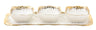 Three small gold rimmed porcelain bowls lined up along a narrow rectangular tray
