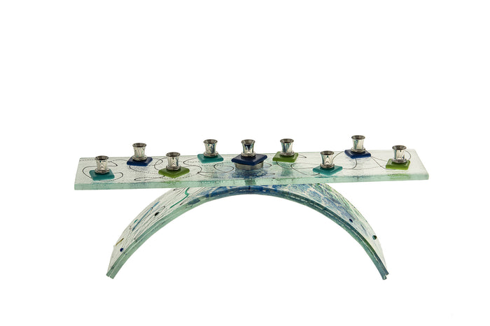Chanukah menorah in blue and green glass with candle holders along a low bar