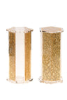 Two hexagonal gold toned lucite shakers standing side by side with faceted panels