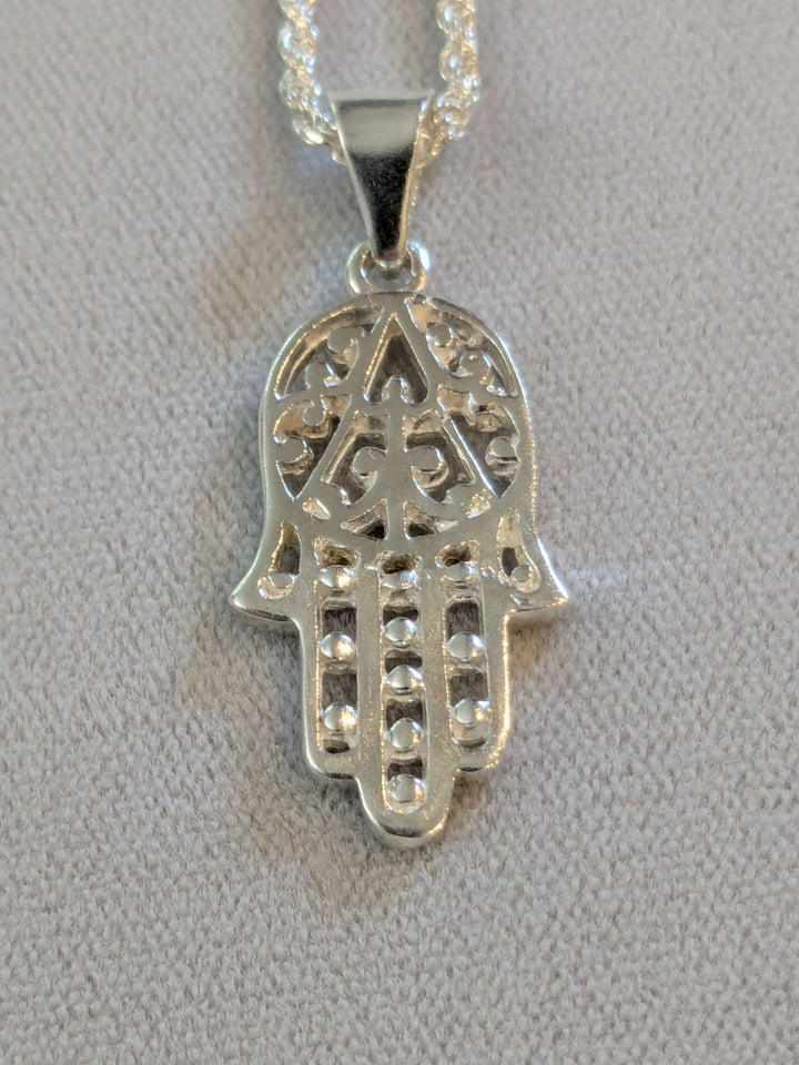 Sterling silver openwork Hamsa with beaded fingers on a rope chain, gray background