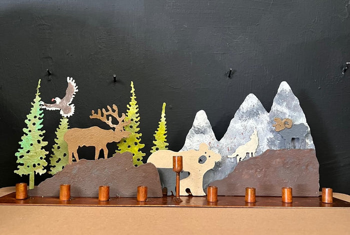 Metal Chanukah menorah cut in the outline of a mountain ridge