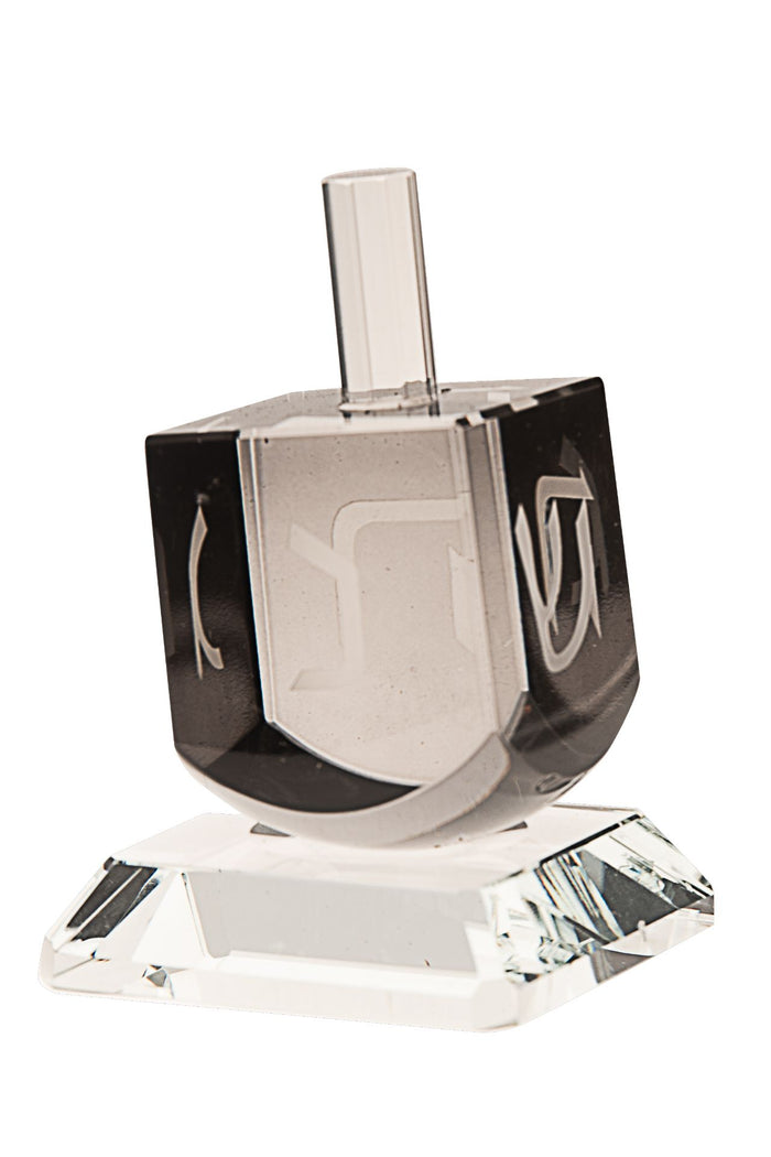 Dark black crystal dreidel with Hebrew letters cut into its four faces above a clear base