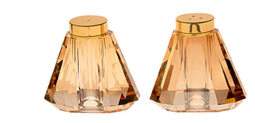 Crystal salt and pepper shakers with gold tone caps catching the light