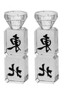 Two short slim crystal candlesticks with narrow square bases standing side by side