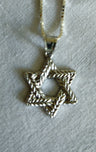 High polished sterling Star of David of braided laurel leaves on a box chain, laid on linen