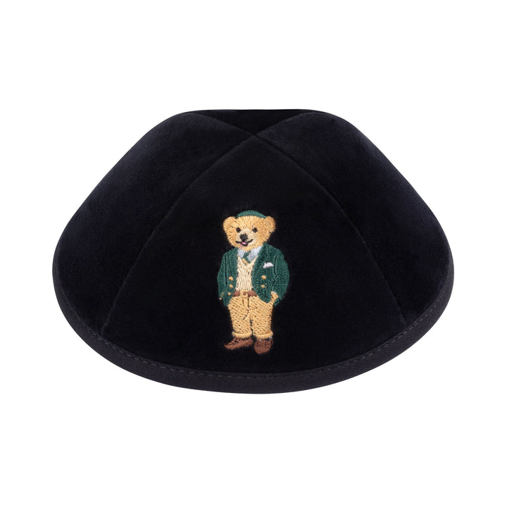Black velvet kippah embroidered with a honey-coloured Dov Bear in a green blazer, cream knit sweater, green cap and tan trousers