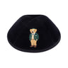 Black velvet kippah embroidered with a honey-coloured Dov Bear in a green blazer, cream knit sweater, green cap and tan trousers