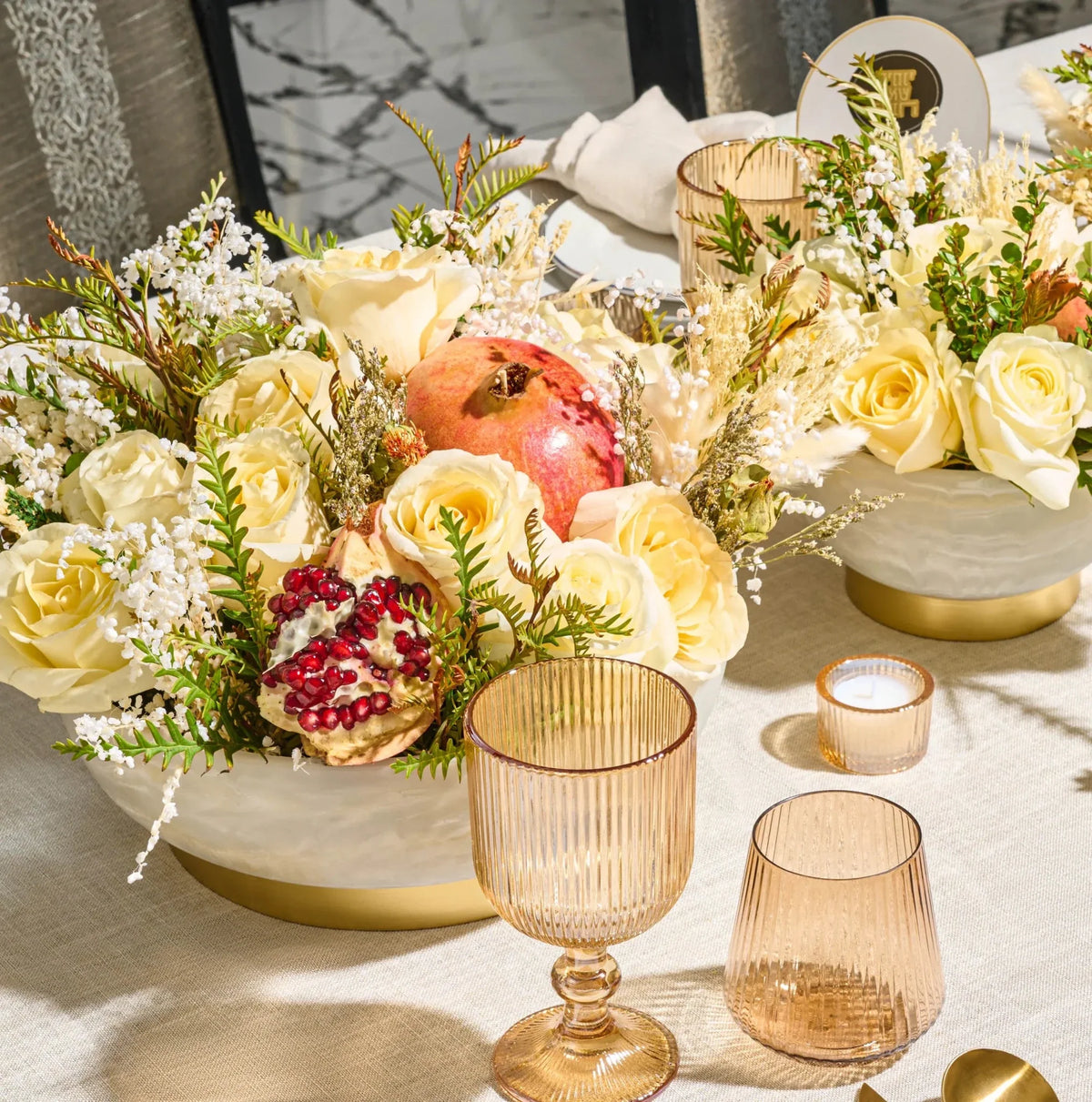 Marbled resin pedestal bowls used as centerpieces with roses, pomegranates and candles on a holiday table