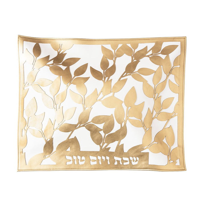 Gold leaf laser-cut challah cover over white with Shabbos V'Yom Tov cut at the bottom