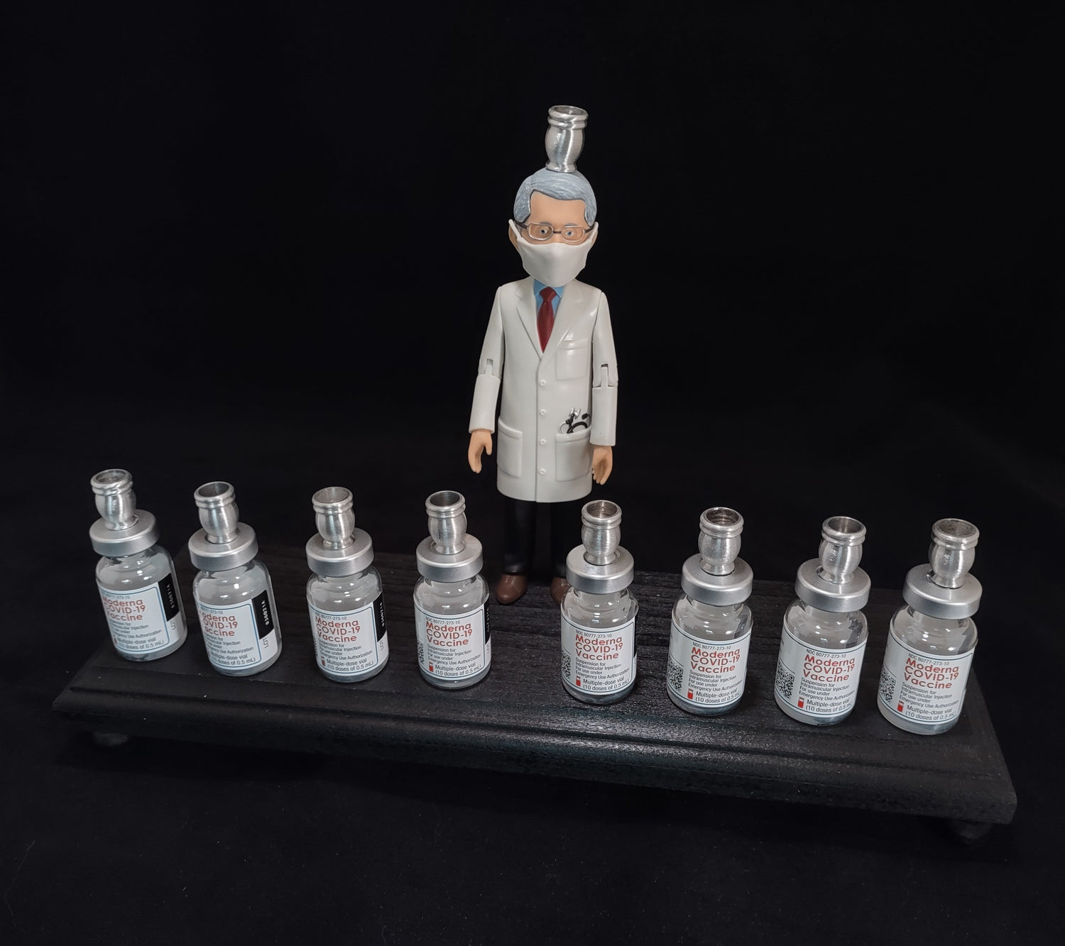 Dr. Fauci Vaccine Menorah — action figure beside repurposed glass vaccine vials | Judaica Square Lakewood (view 3)