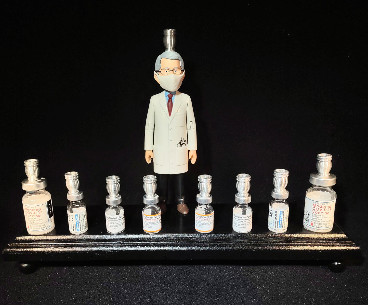 Dr. Fauci Vaccine Menorah — action figure beside repurposed glass vaccine vials | Judaica Square Lakewood (view 5)