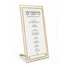 Gold-rimmed white marble lucite Simanim card on tabletop stand