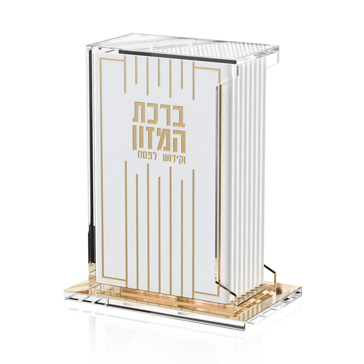 Linear Pesach bencher and kiddush set in gold, white benchers in a lucite holder on a mirrored base