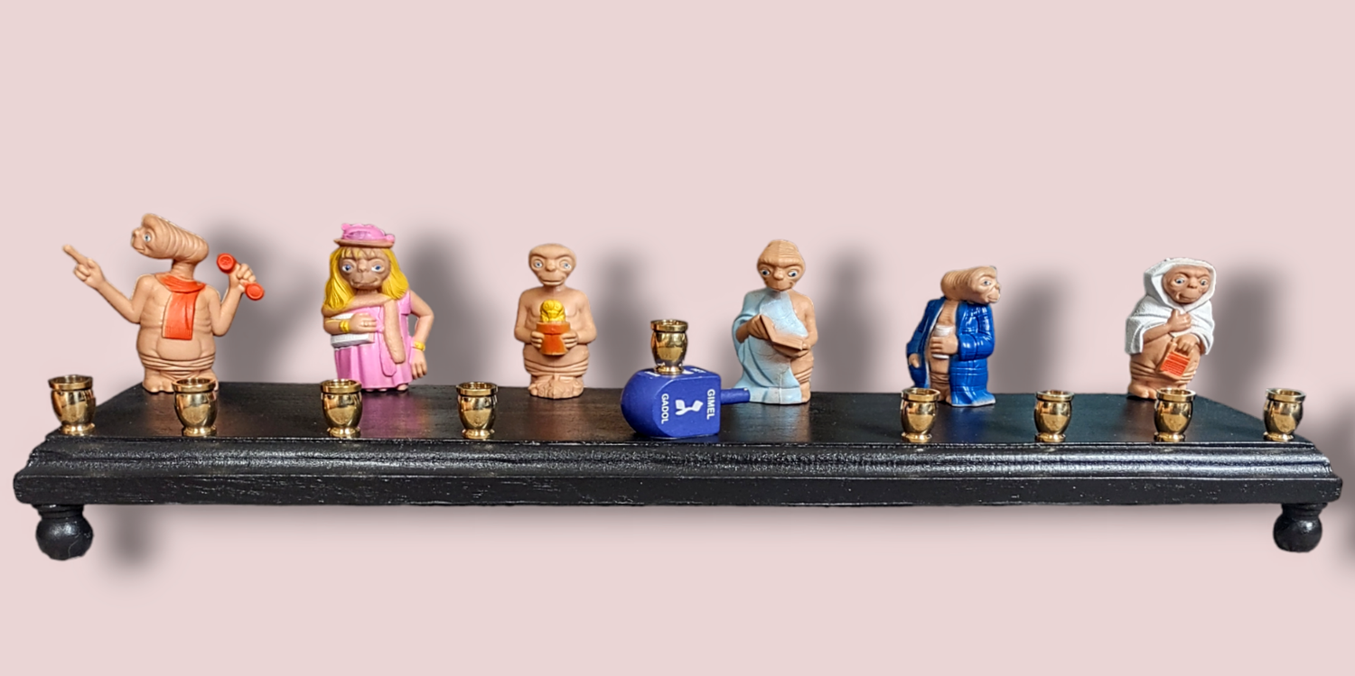 E.T. dress up menorah — six costumed E.T. toy figures along a painted plaque | Judaica Square Lakewood (view 2)