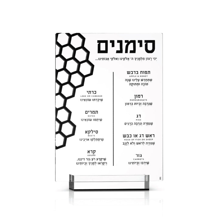 Clear simanim card with a black honeycomb cut-out standing in its lucite base, front on