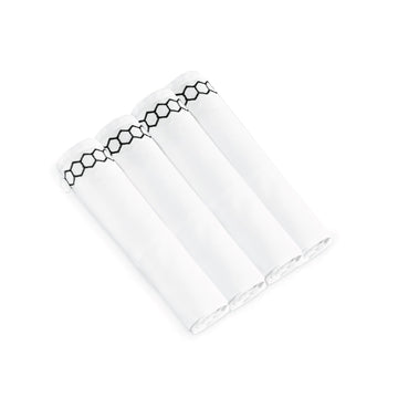 Four white napkins rolled side by side showing the black honeycomb embroidered border