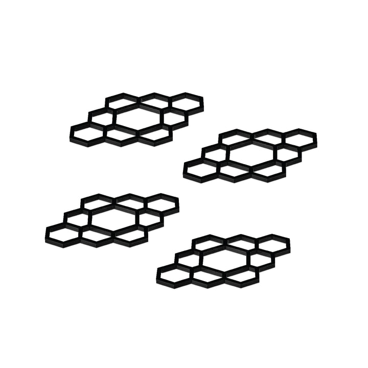 Four black lucite honeycomb napkin rings arranged on white