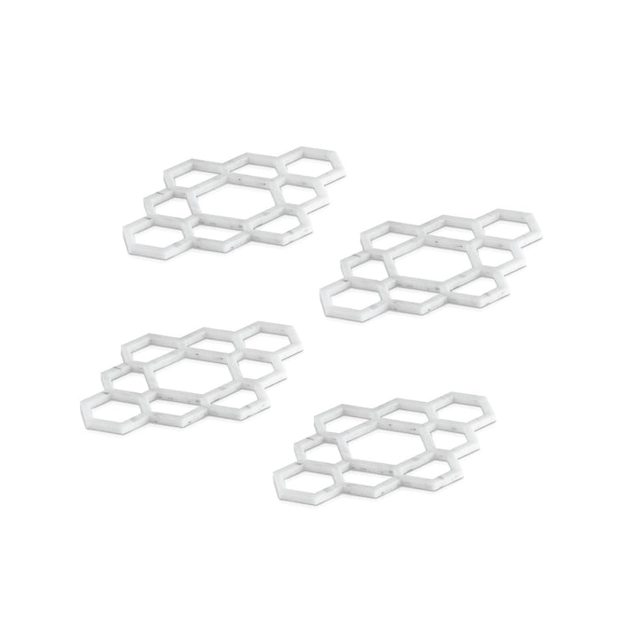Four white marble lucite honeycomb napkin rings arranged on white