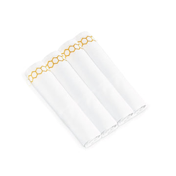 Four rolled napkins with gold honeycomb embroidery along the border