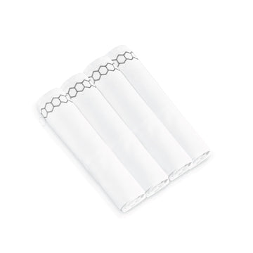 Four rolled napkins showing the silver honeycomb embroidered border