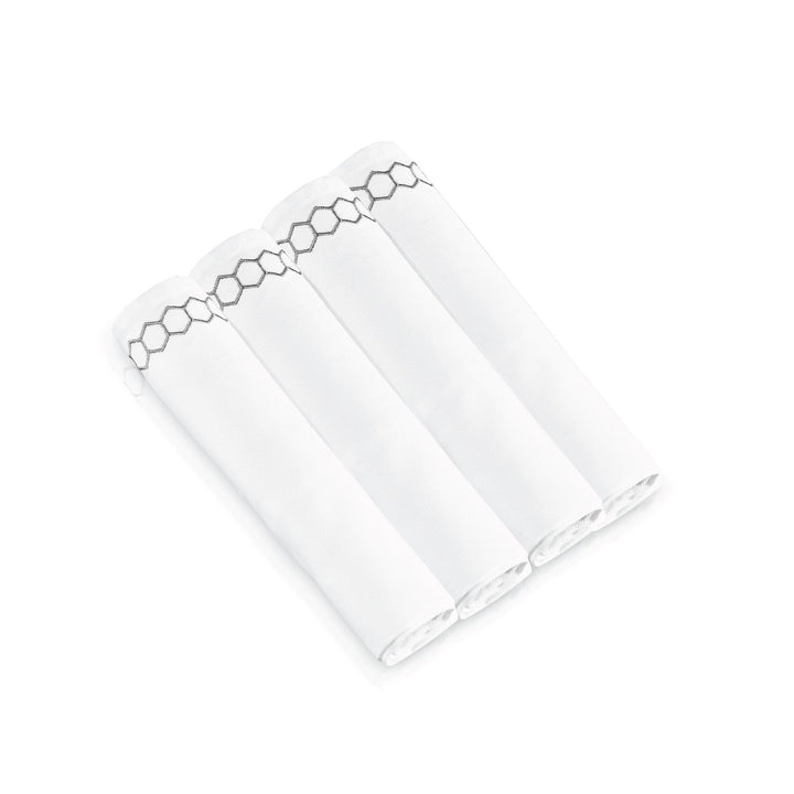 Four rolled napkins showing the silver honeycomb embroidered border