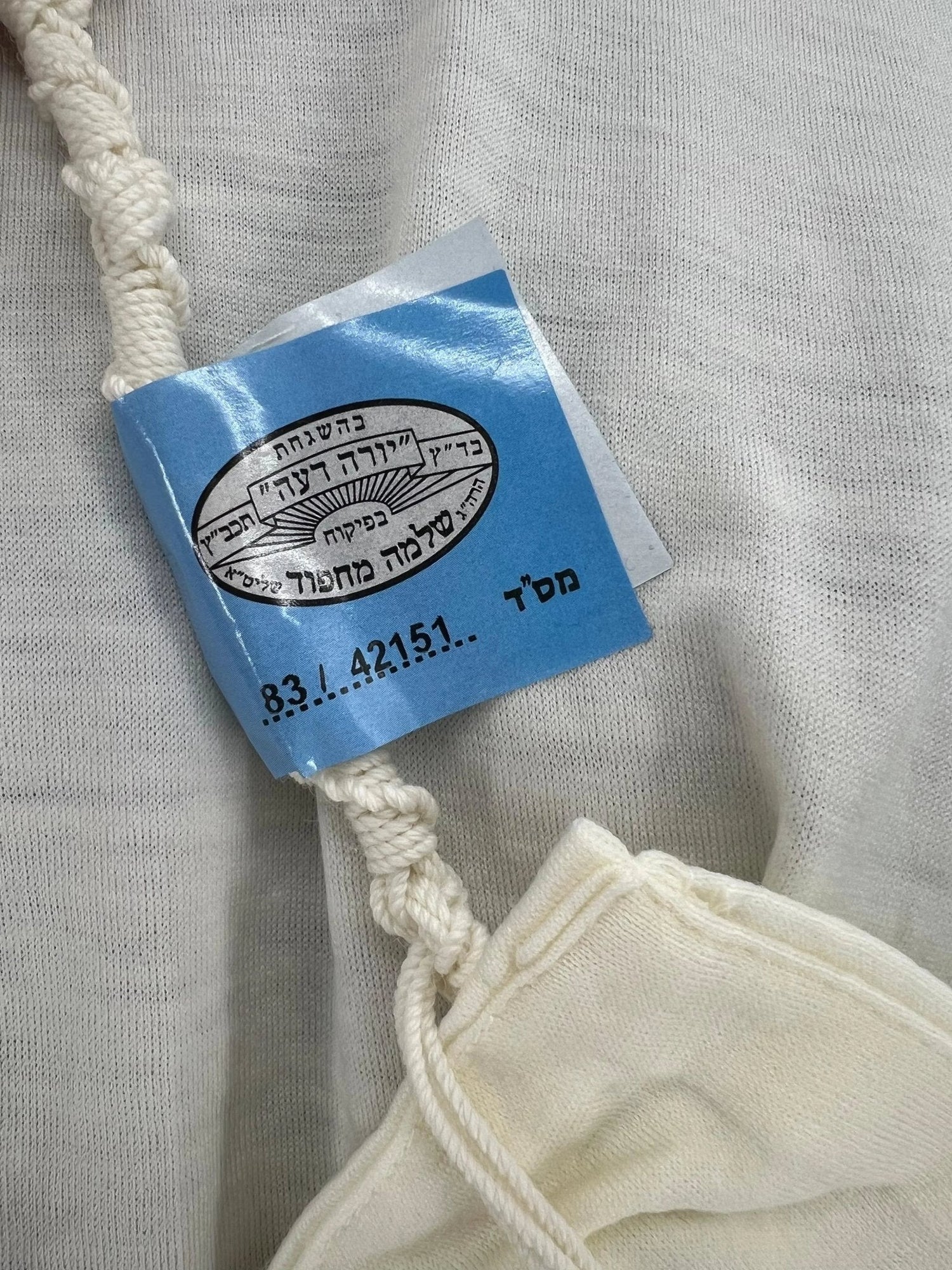 Wool tzitzit garment corner with knotted strings and kosher tag