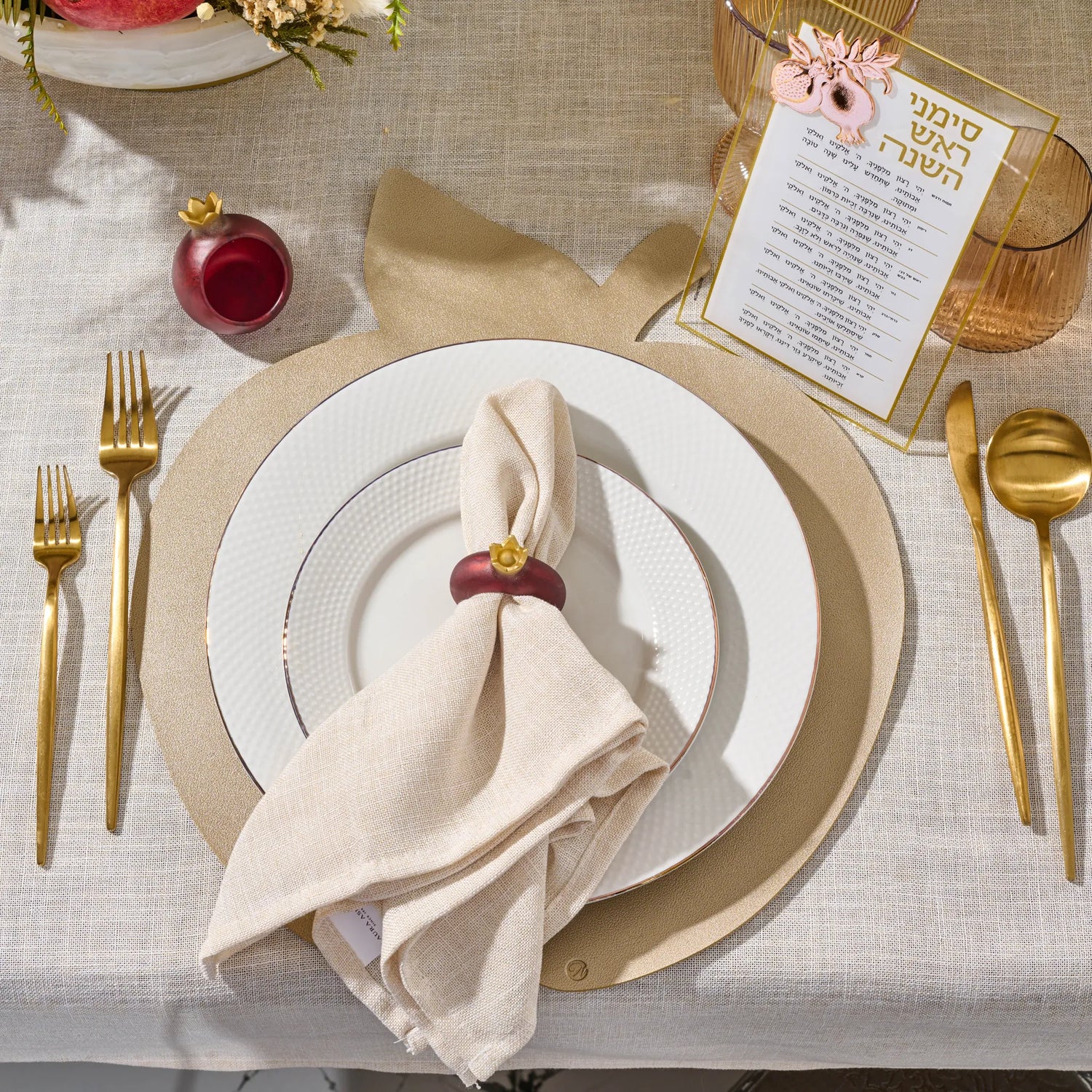 Deep red pomegranate napkin ring at a Rosh Hashanah place setting with simanim card