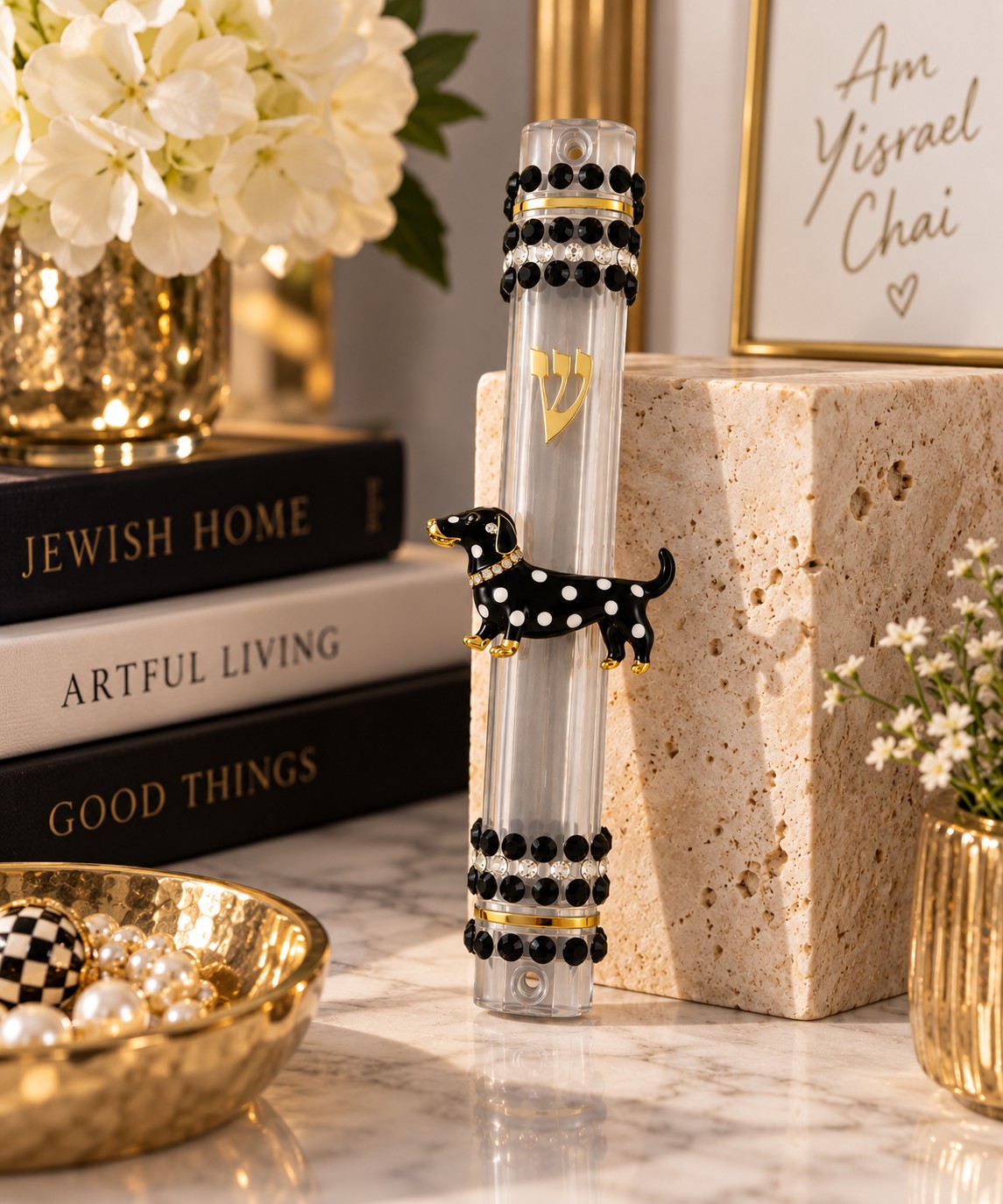 Dottie mezuzah case displayed on a shelf beside books and flowers