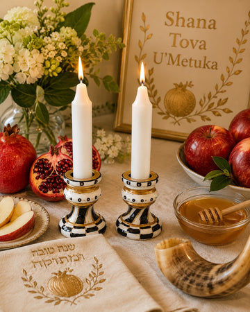 Golda Hand-Painted Shabbat Candlesticks, black, ivory and gold candlesticks with lit candles on a Rosh Hashanah table