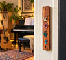 Wood mezuzah case with music notes on a doorpost by a piano room
