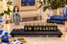 Kamala Harris figure beside I'M SPEAKING letter blocks with candle cups
