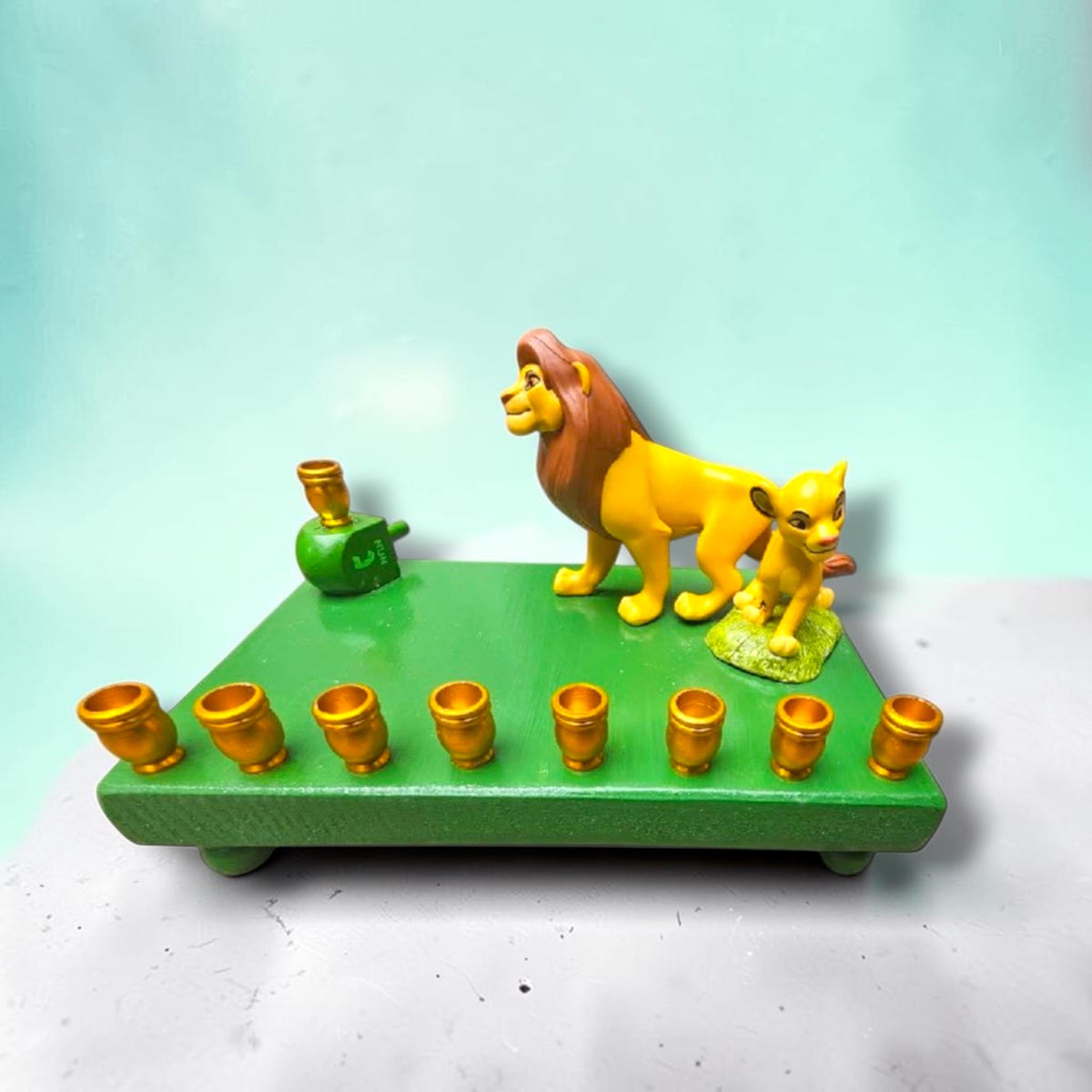 Lion King Simba & Mufasa Menorah, green base with Simba and Mufasa figures and gold candle cups, front view