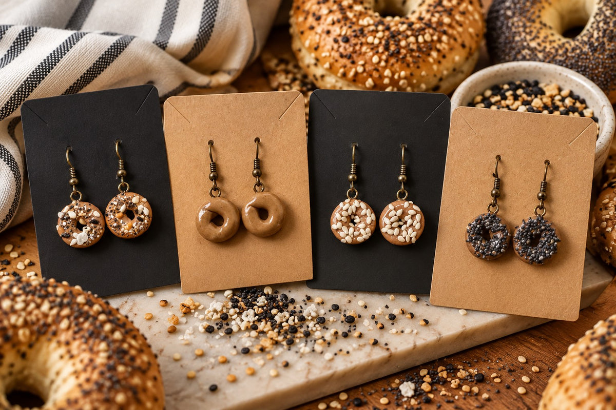 Four pairs of mini bagel earrings on cards with bagels