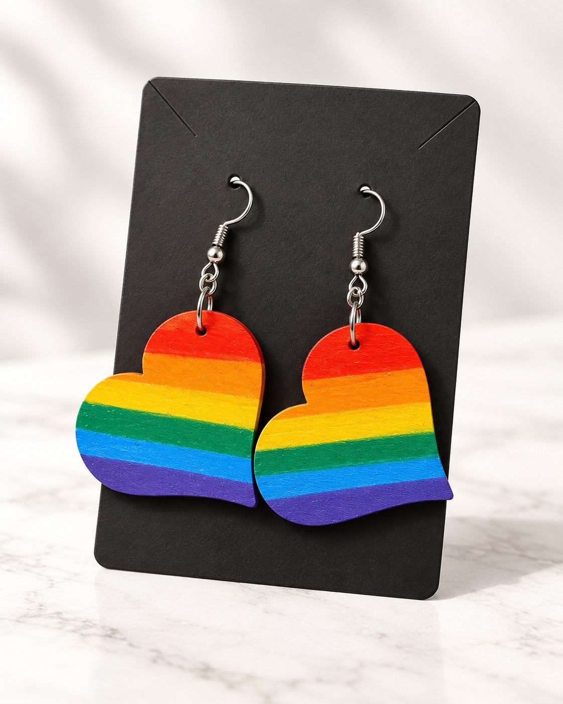 Rainbow heart earrings on a black card on white