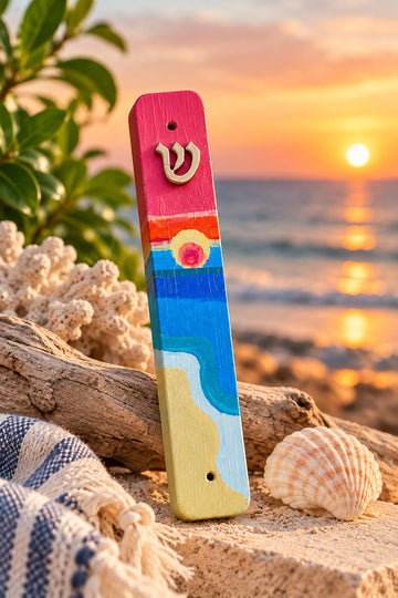 Shalom Shores Mezuzah Case, beach-painted mezuzah on sand at sunset