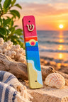 Shalom Shores Mezuzah Case, beach-painted mezuzah on sand at sunset