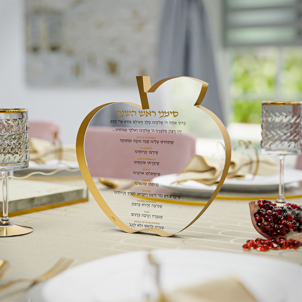 Simanim block standing on a set Rosh Hashanah table beside crystal glasses and pomegranate seeds