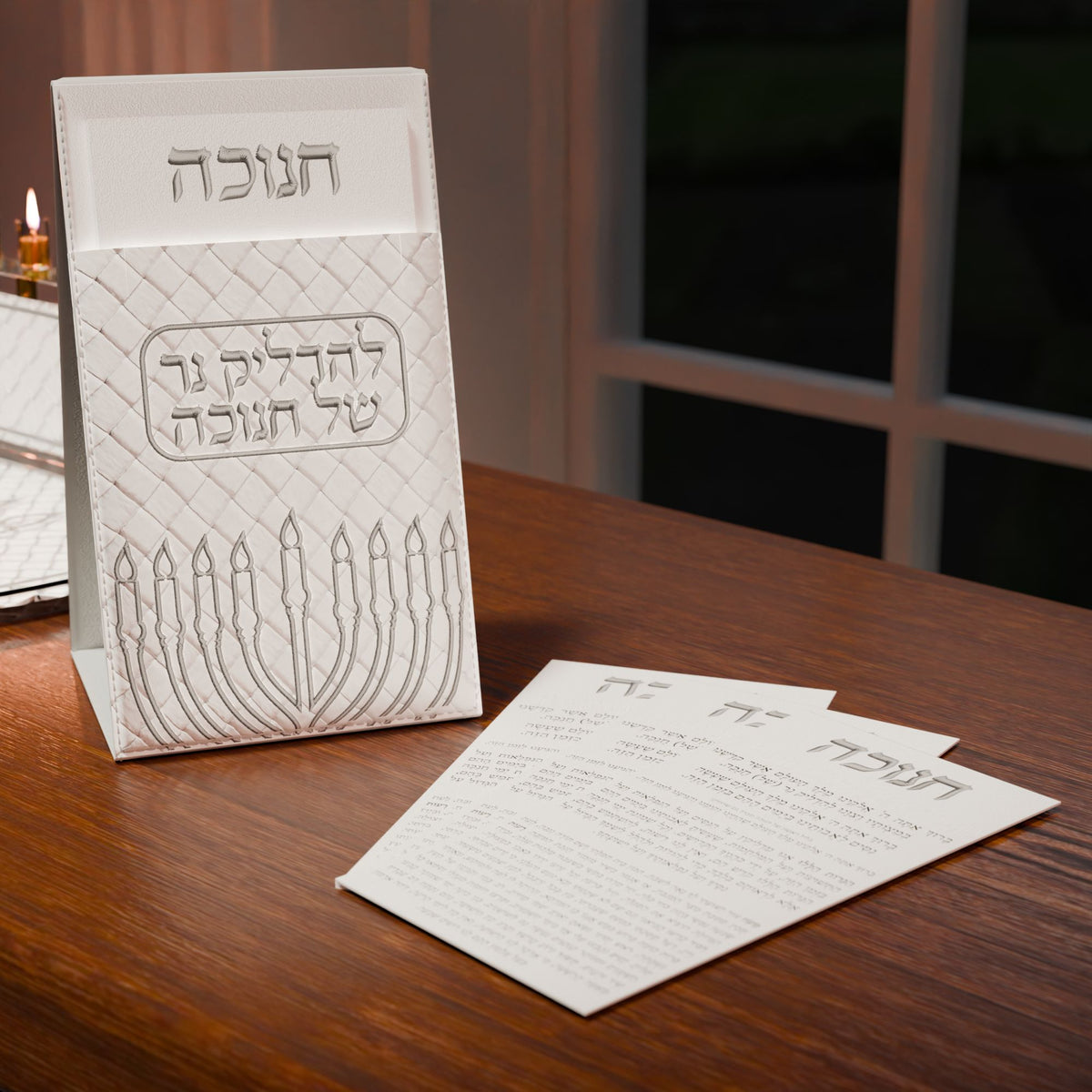 Silver Chanukah brochos pouch and cards set out on a dark wood table by the window