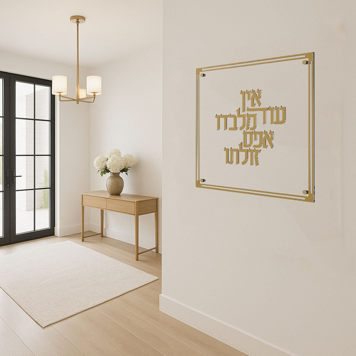 Gold plaque hanging in a bright entryway above a wooden console table with flowers