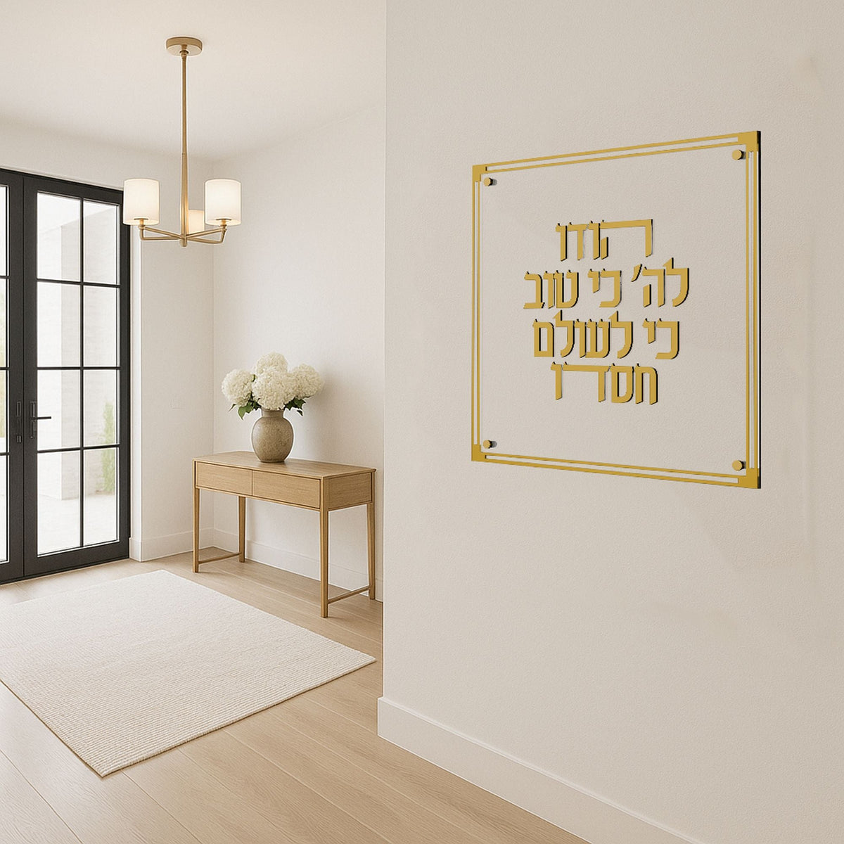 Gold Hodu Lashem plaque hung in a bright hallway above a wooden console table