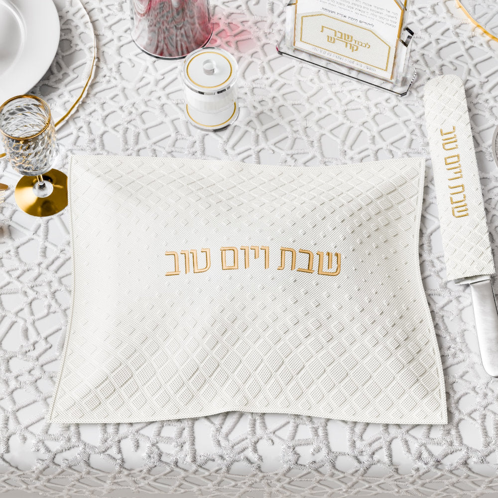 Gold-lettered cover on a set table beside the matching knife cover and a lidded cup