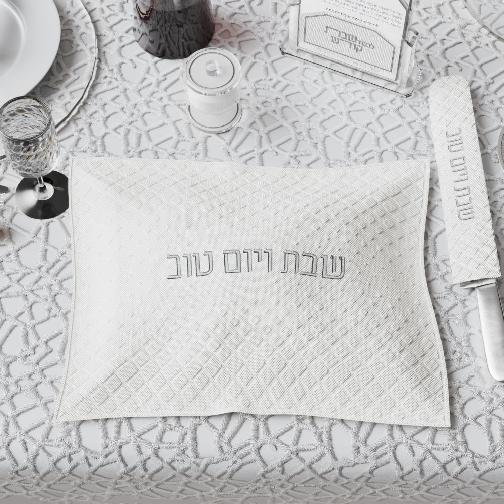 Silver-lettered diamond cover on the Shabbos table with the matching knife cover alongside